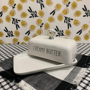 Displayed open creamy white ceramic butter keeper with black print and crystal knob