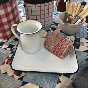 White enamel tray with blue trim displayed with small pitcher and red & white buckets 
