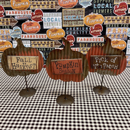 Metal Fall pumpkins on stands with message signs on salvaged wood