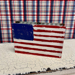 Small corrugated metal box sign with red, white and blue flag.