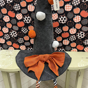 Black Halloween hat with white pom poms, orange bow and dangle legs
