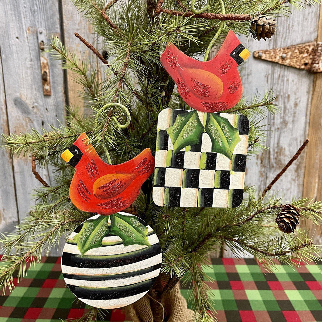 Metal Redbird Christmas ornaments atop black and white checks and stripes