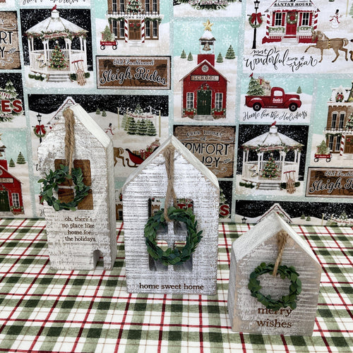 Wooden block holiday houses with seasonal messages and small hanging wreaths